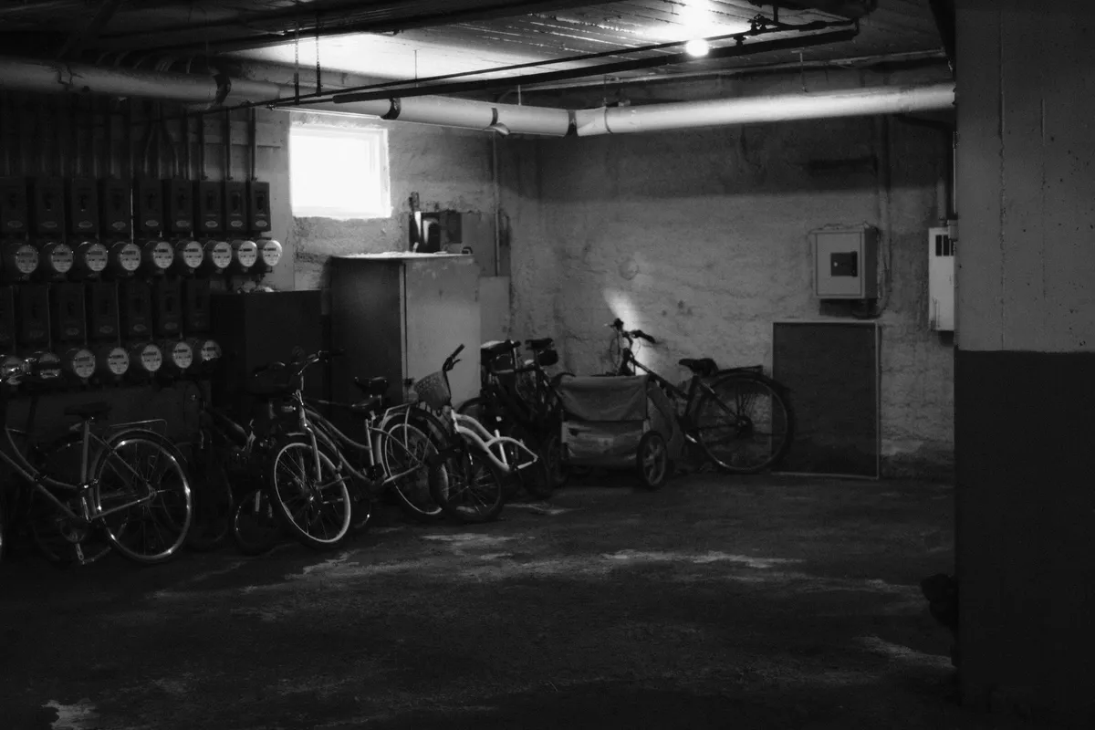 Kellerraum in Schwarzweiss mit abgestellten Fahrrädern und einer Wand voller alter Zähler